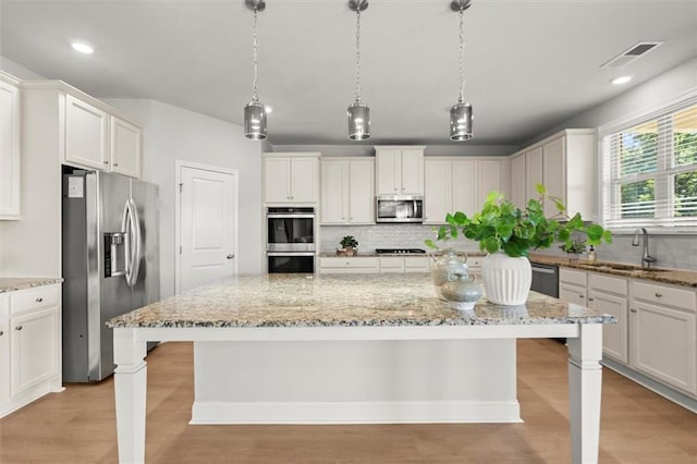 7410 Ansley View Ln, Cumming, GA 30028 - kitchen with appliances with stainless steel finishes, decorative backsplash, a breakfast bar, light wood-style flooring, and recessed lighting