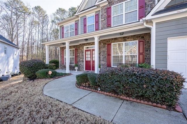 doorway to property featuring stone siding, covered porch, and board and batten siding