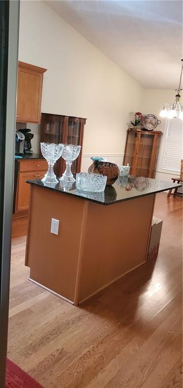 999 Simonton Glen Dr, Lawrenceville, GA 30045 - kitchen featuring light wood finished floors, a chandelier, lofted ceiling, a kitchen island, and decorative light fixtures