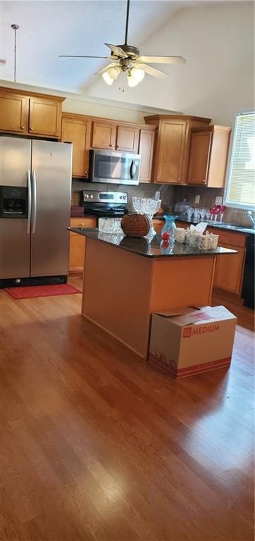 999 Simonton Glen Dr, Lawrenceville, GA 30045 - kitchen featuring stainless steel appliances, light wood-style floors, dark countertops, ceiling fan, and high vaulted ceiling