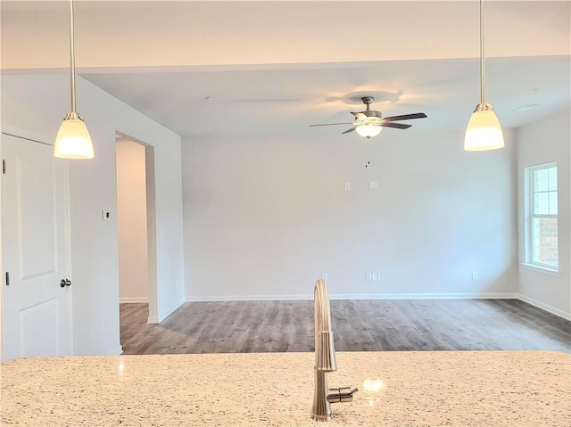 unfurnished room with a ceiling fan, baseboards, and wood finished floors