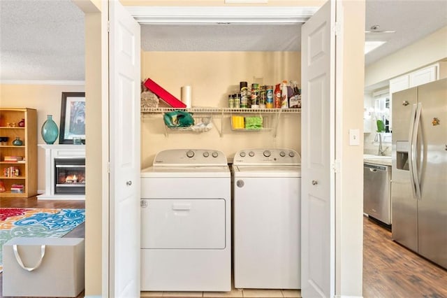 laundry room with independent washer and dryer, wood finished floors, a textured ceiling, a glass covered fireplace, and crown molding