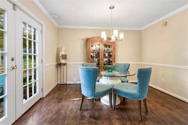 dining space featuring a chandelier, a textured ceiling, wood finished floors, baseboards, and crown molding