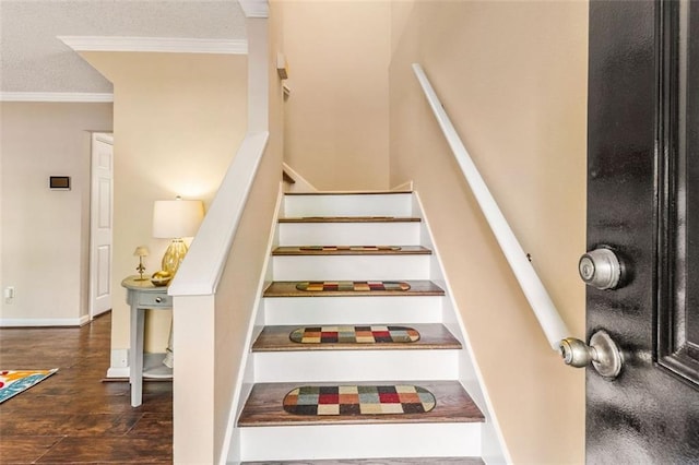 stairway with ornamental molding, wood finished floors, and a textured ceiling