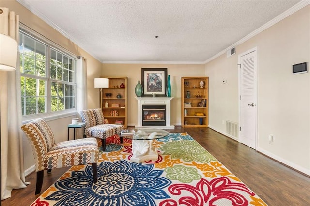 living area featuring wood finished floors, a textured ceiling, a glass covered fireplace, crown molding, and baseboards