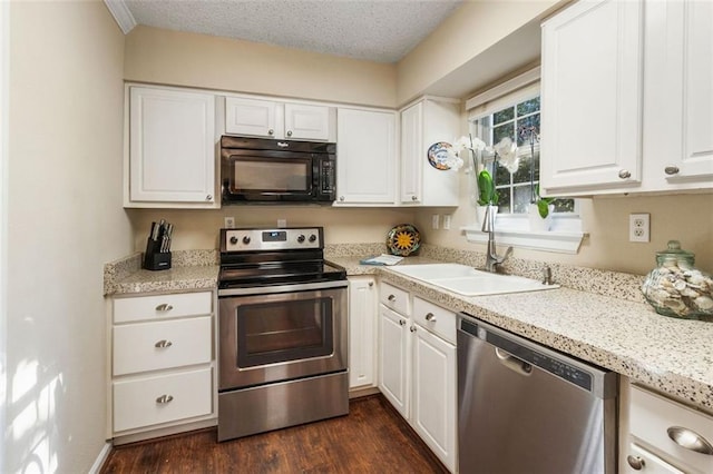 kitchen with appliances with stainless steel finishes, a sink, white cabinetry, dark wood-type flooring, and a textured ceiling