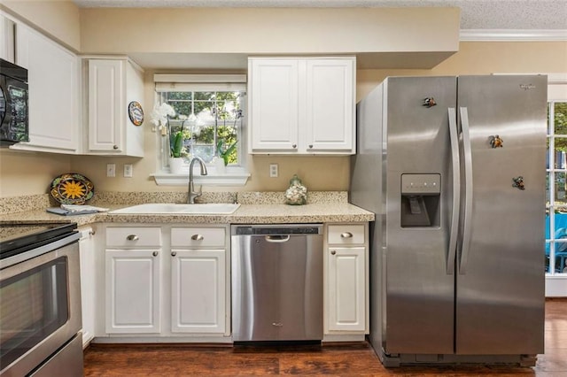 kitchen with stainless steel appliances, a sink, light countertops, white cabinets, and crown molding