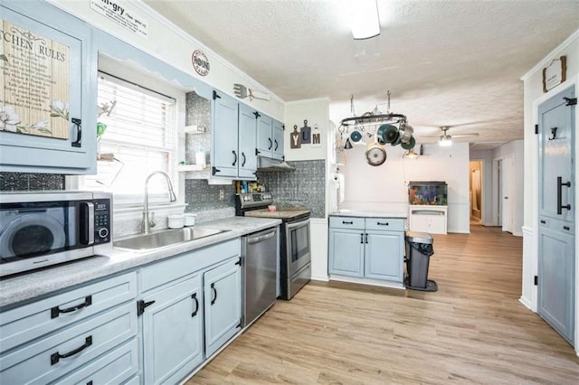 kitchen featuring stainless steel appliances, sink, backsplash, and light wood-type flooring