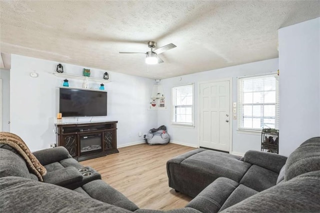 living room with ceiling fan, a textured ceiling, and light hardwood / wood-style floors