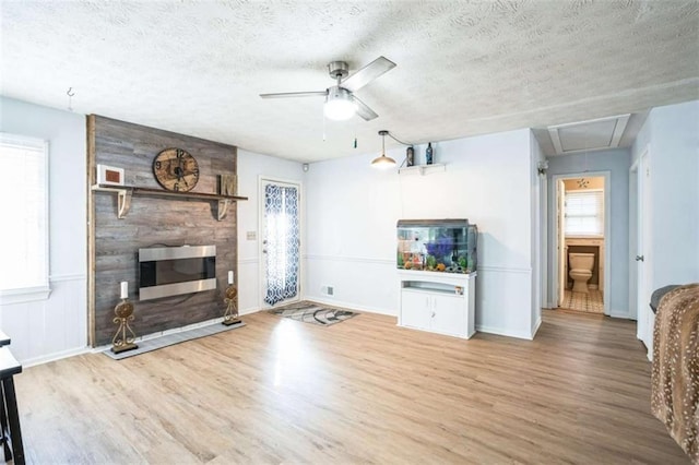 unfurnished living room featuring ceiling fan, hardwood / wood-style flooring, a large fireplace, and a textured ceiling