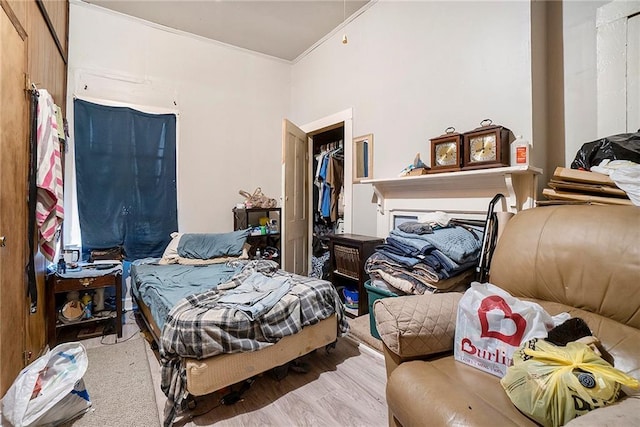 bedroom featuring a closet, light wood-type flooring, and ornamental molding