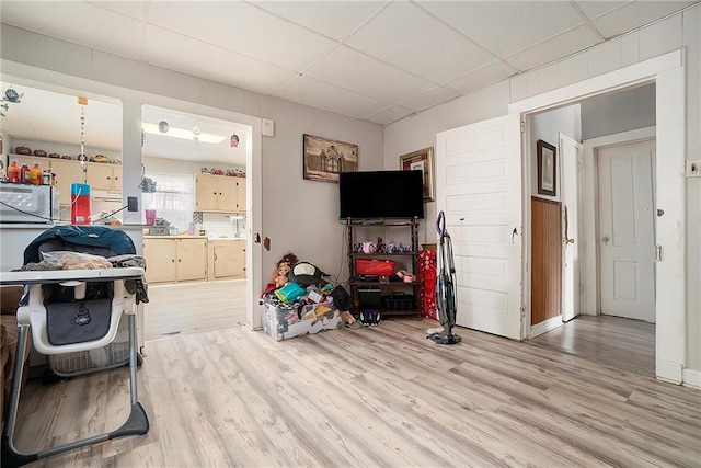 living room with a drop ceiling and light hardwood / wood-style floors