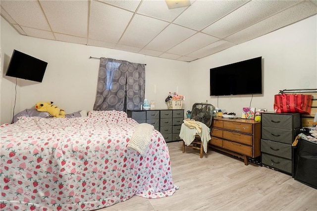 bedroom with light wood-type flooring and a drop ceiling