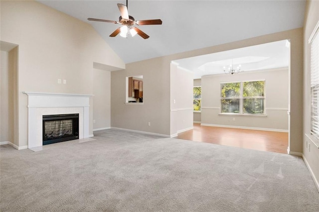 unfurnished living room with light carpet, high vaulted ceiling, and ceiling fan with notable chandelier