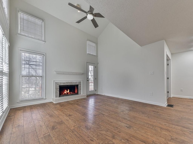 unfurnished living room featuring ceiling fan, hardwood / wood-style floors, a textured ceiling, and high vaulted ceiling