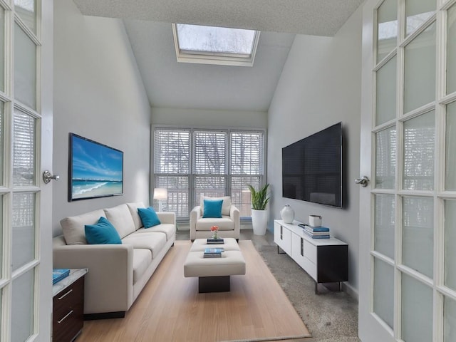 carpeted living room featuring vaulted ceiling with skylight