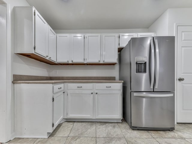 kitchen featuring white cabinets, light tile patterned flooring, and stainless steel fridge