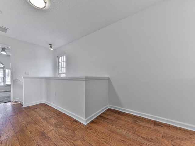 empty room with plenty of natural light, hardwood / wood-style floors, and a textured ceiling