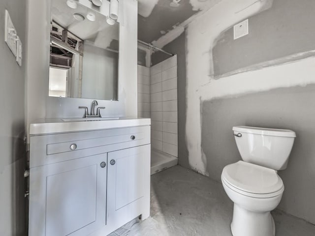 bathroom with vanity, concrete floors, toilet, and a shower