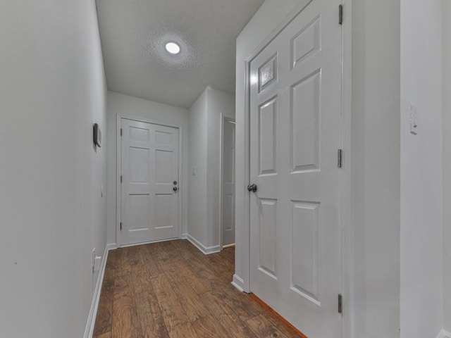 hall with a textured ceiling and dark hardwood / wood-style flooring