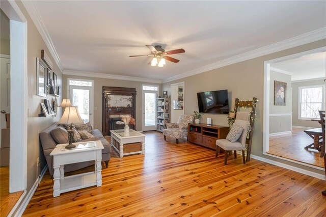 living area featuring light wood-style floors, a fireplace, and crown molding