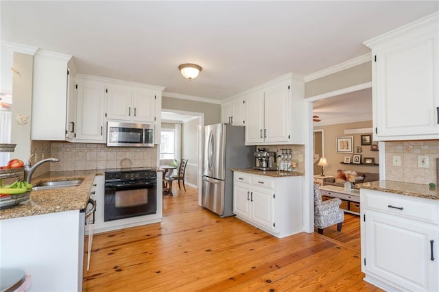 kitchen with light wood-type flooring, appliances with stainless steel finishes, white cabinets, and a sink