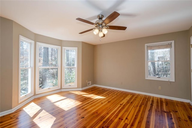 spare room with a healthy amount of sunlight, baseboards, and hardwood / wood-style floors