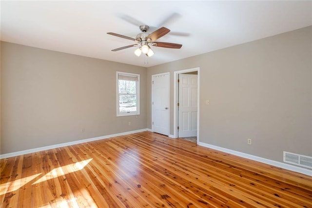 unfurnished room featuring light wood finished floors, baseboards, visible vents, and a ceiling fan