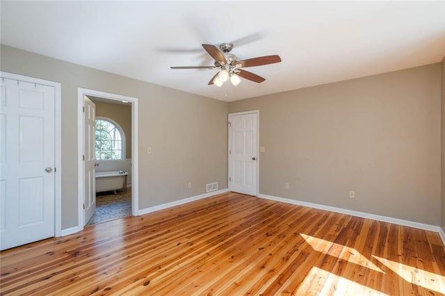 spare room with a ceiling fan, light wood-type flooring, visible vents, and baseboards