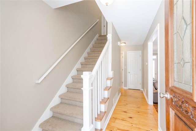 entryway featuring light wood-style floors, baseboards, and stairs