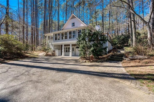 view of front facade featuring driveway, a sunroom, and a chimney