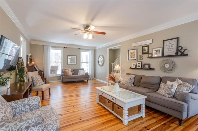 living room featuring baseboards, a ceiling fan, stairway, crown molding, and light wood-type flooring