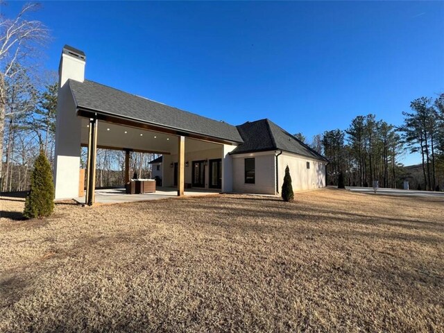 back of property with a patio area, a chimney, and roof with shingles
