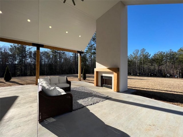 view of patio / terrace with an outdoor living space with a fireplace and ceiling fan