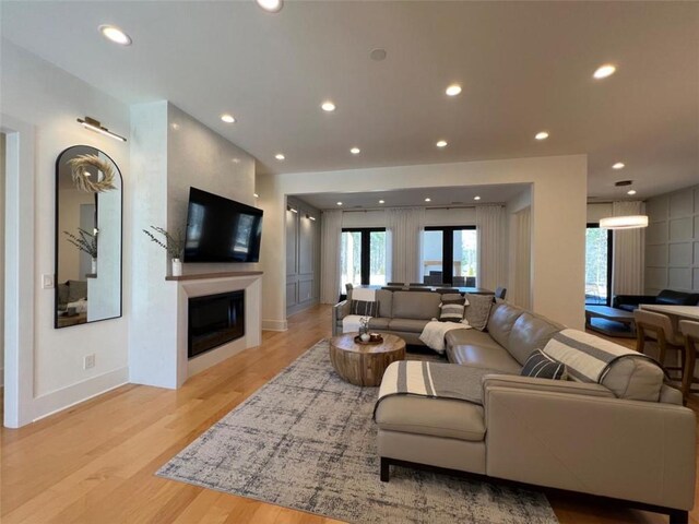 living area featuring baseboards, light wood finished floors, a fireplace, and recessed lighting