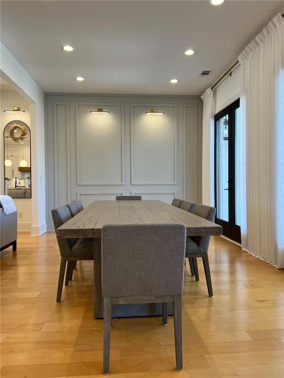 dining space featuring light wood finished floors, visible vents, a decorative wall, and recessed lighting