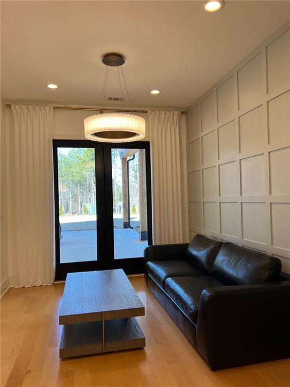 living room with light wood finished floors, a decorative wall, french doors, and recessed lighting