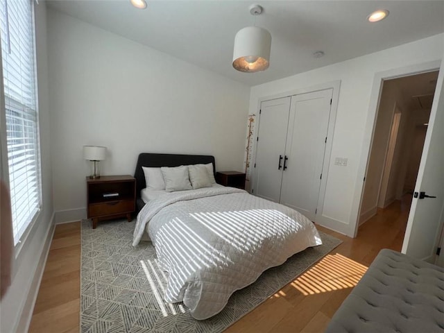 bedroom with light wood-style flooring, baseboards, a closet, and recessed lighting