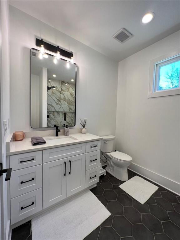full bath featuring a marble finish shower, visible vents, baseboards, tile patterned flooring, and vanity