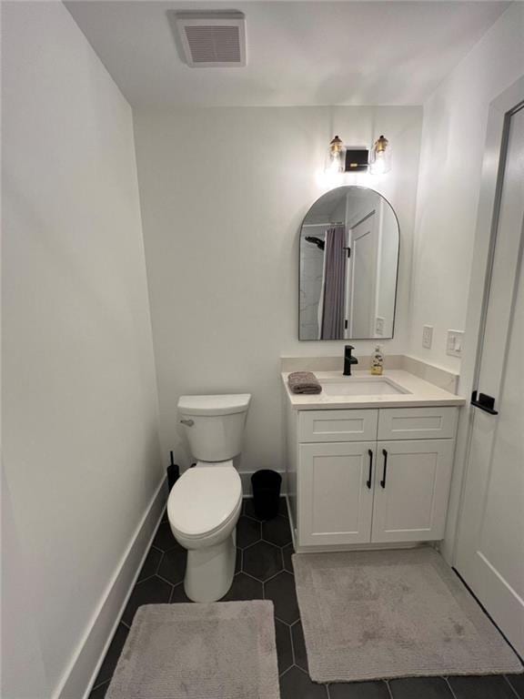 bathroom featuring tile patterned flooring, toilet, vanity, visible vents, and baseboards