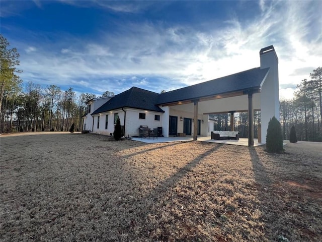 rear view of house featuring a patio, a chimney, and an outdoor hangout area