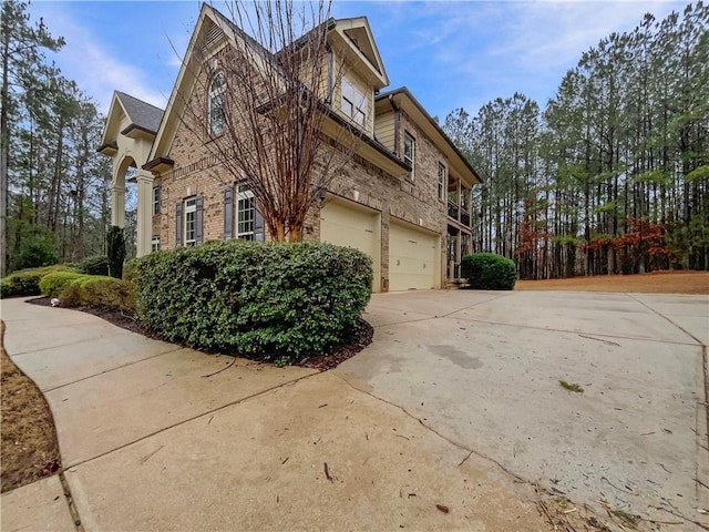 view of side of home with a garage, brick siding, and concrete driveway