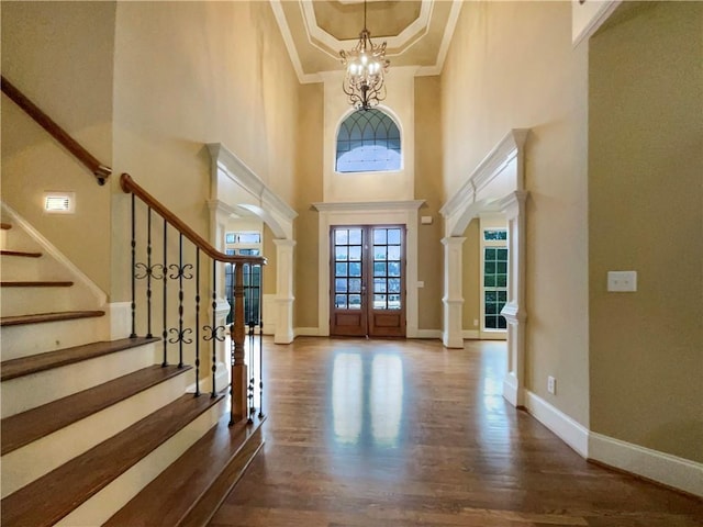 entryway with an inviting chandelier, wood finished floors, baseboards, and arched walkways