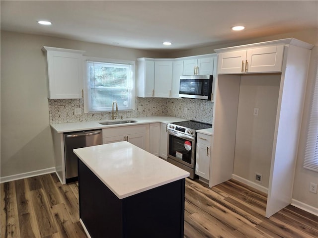 kitchen with stainless steel appliances, white cabinets, a sink, and wood finished floors