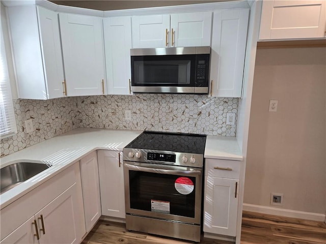 kitchen featuring light wood finished floors, tasteful backsplash, white cabinetry, and stainless steel appliances