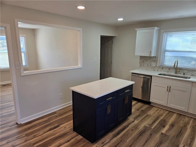 kitchen with light countertops, white cabinets, a sink, wood finished floors, and dishwasher