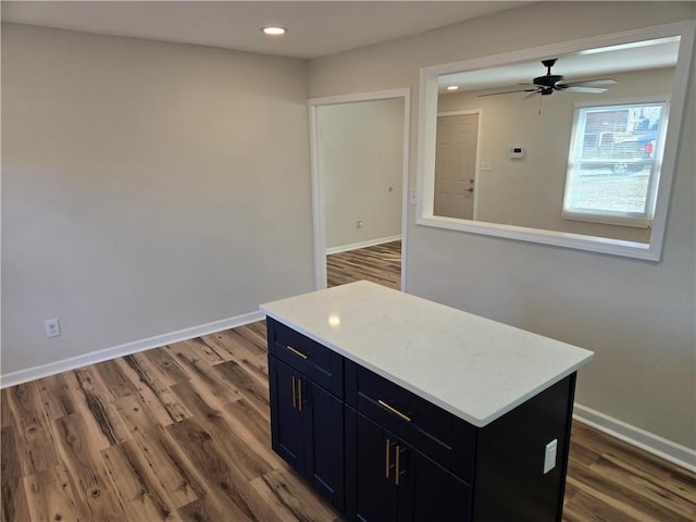 kitchen with light countertops, dark cabinetry, dark wood-style flooring, and baseboards