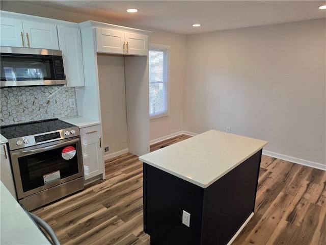 kitchen featuring backsplash, stainless steel appliances, light countertops, and wood finished floors