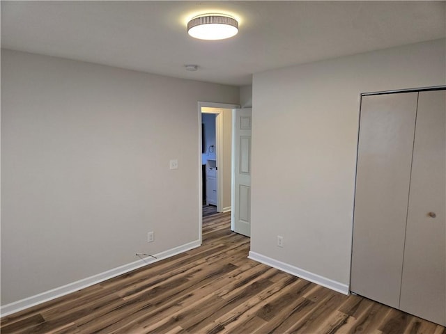 unfurnished bedroom featuring a closet, baseboards, and dark wood-type flooring