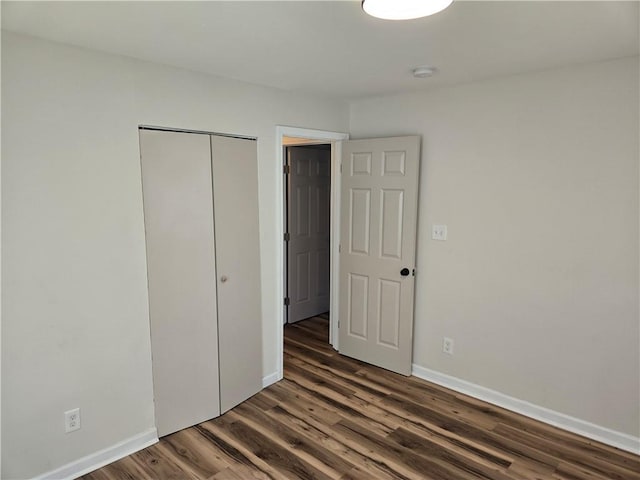 unfurnished bedroom featuring a closet, wood finished floors, and baseboards